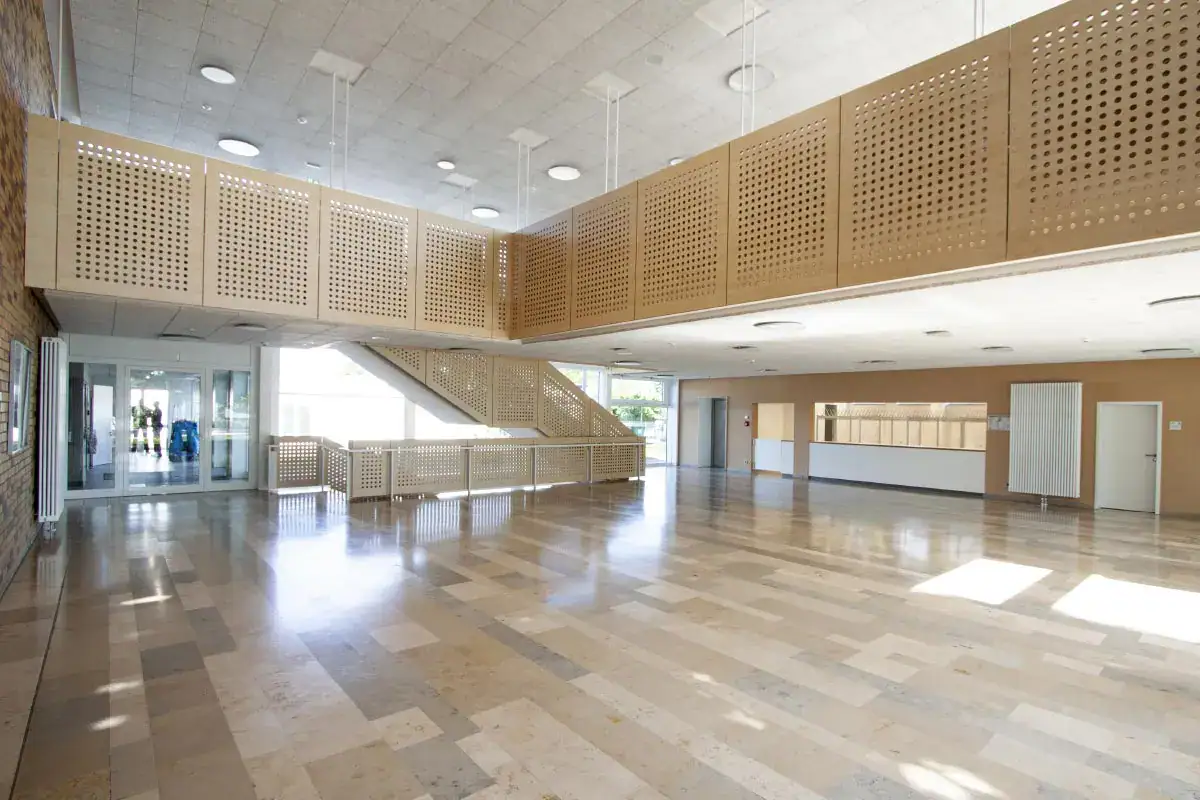 Moderne Empfangshalle mit Holzdekor, viel Tageslicht und offenem Raumkonzept.