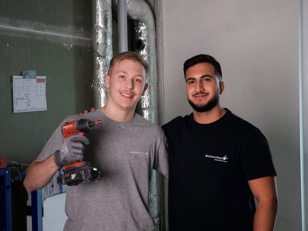 Zwei junge Handwerker mit Werkzeug im Technikraum, smiling.